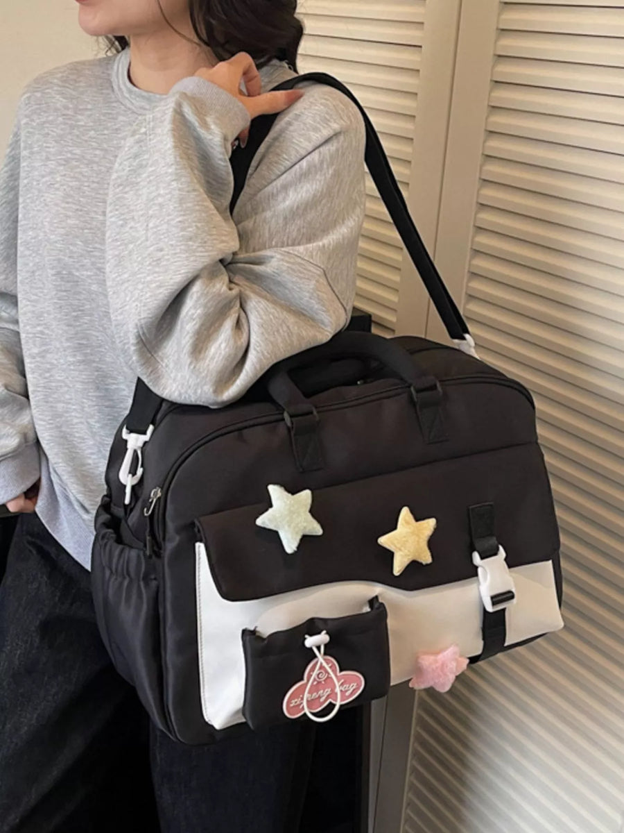 Person holding a black duffel bag with star and cartoon character designs.