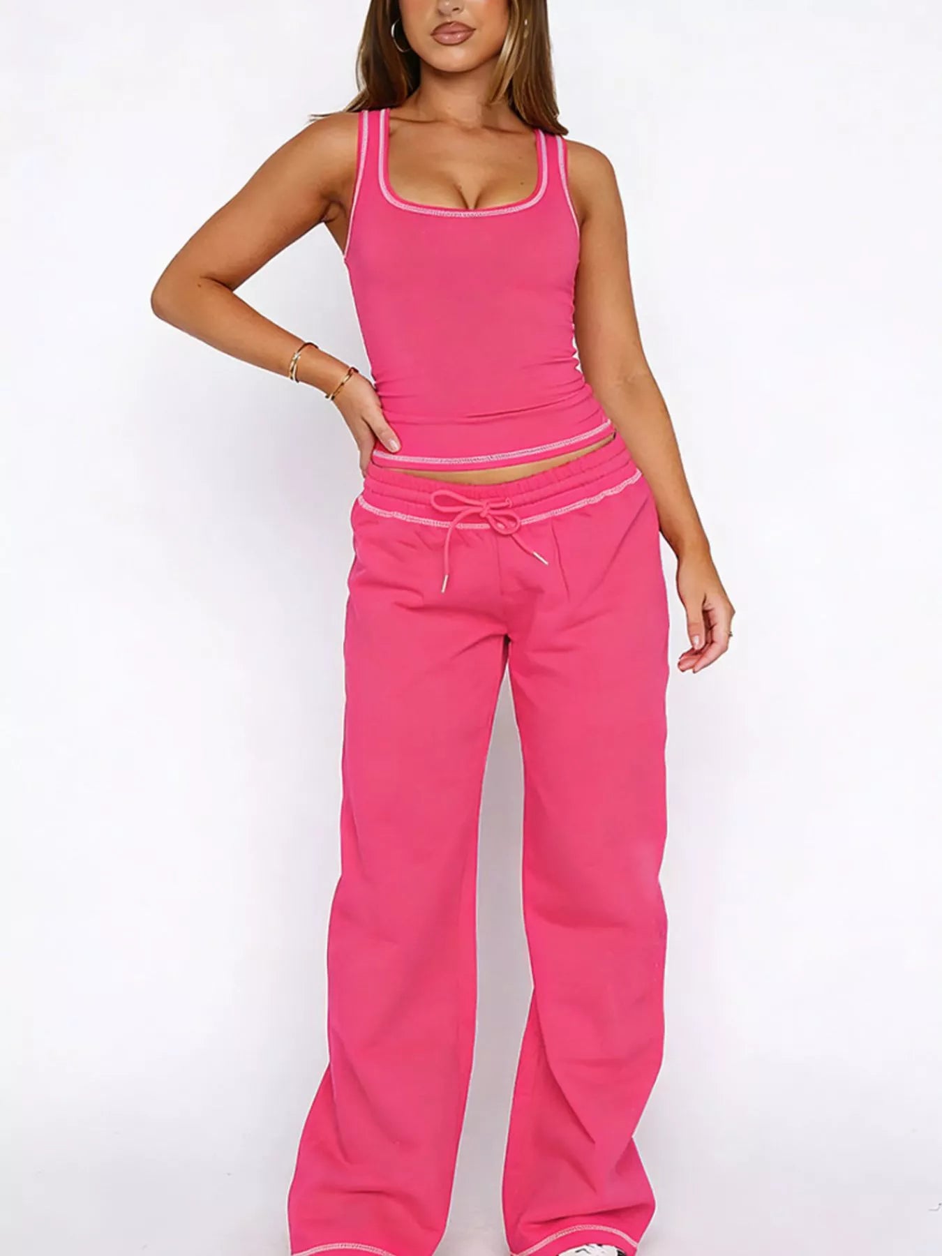 Woman wearing a pink tank top and pants set on a white background