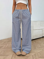 Person wearing blue and white striped pants with a white top in a room.