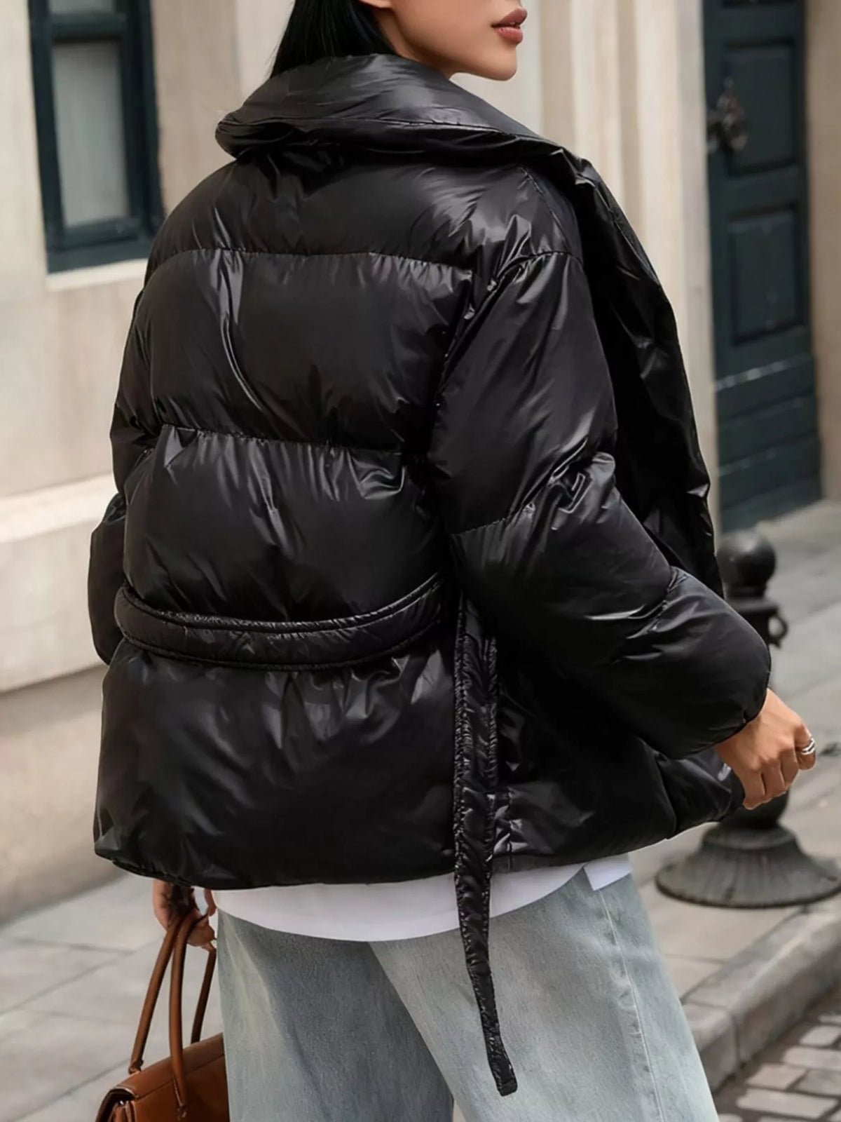 Person wearing a black puffer jacket on a city street.
