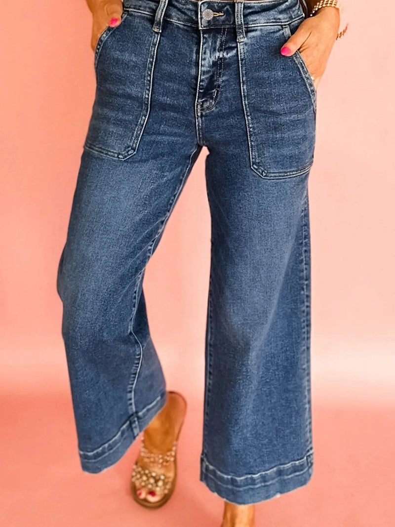 Person wearing blue jeans on a pink background