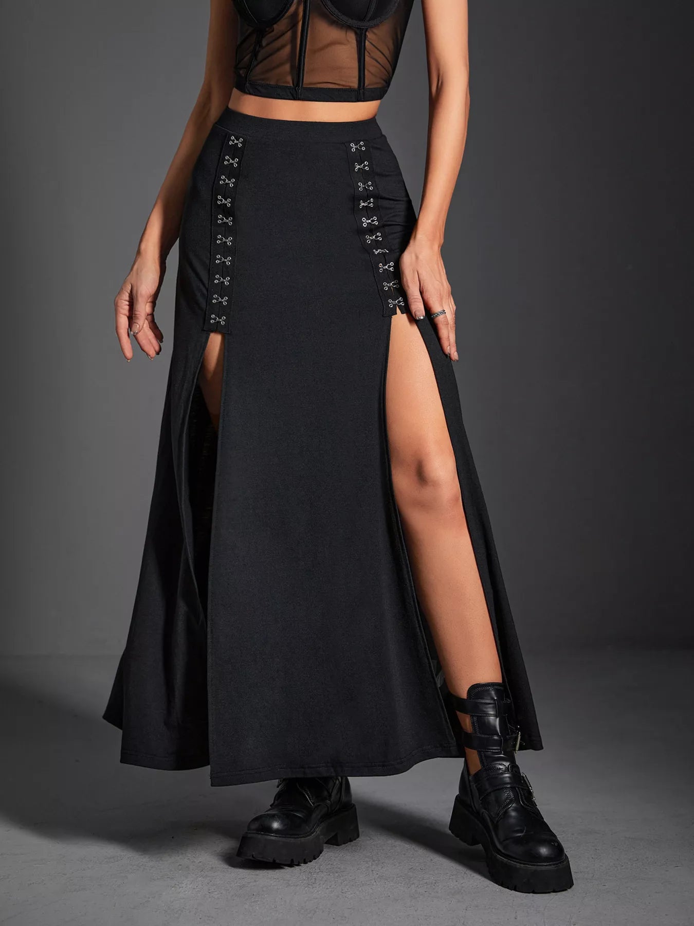 Person wearing a black lace-up skirt with a high slit on a gray background