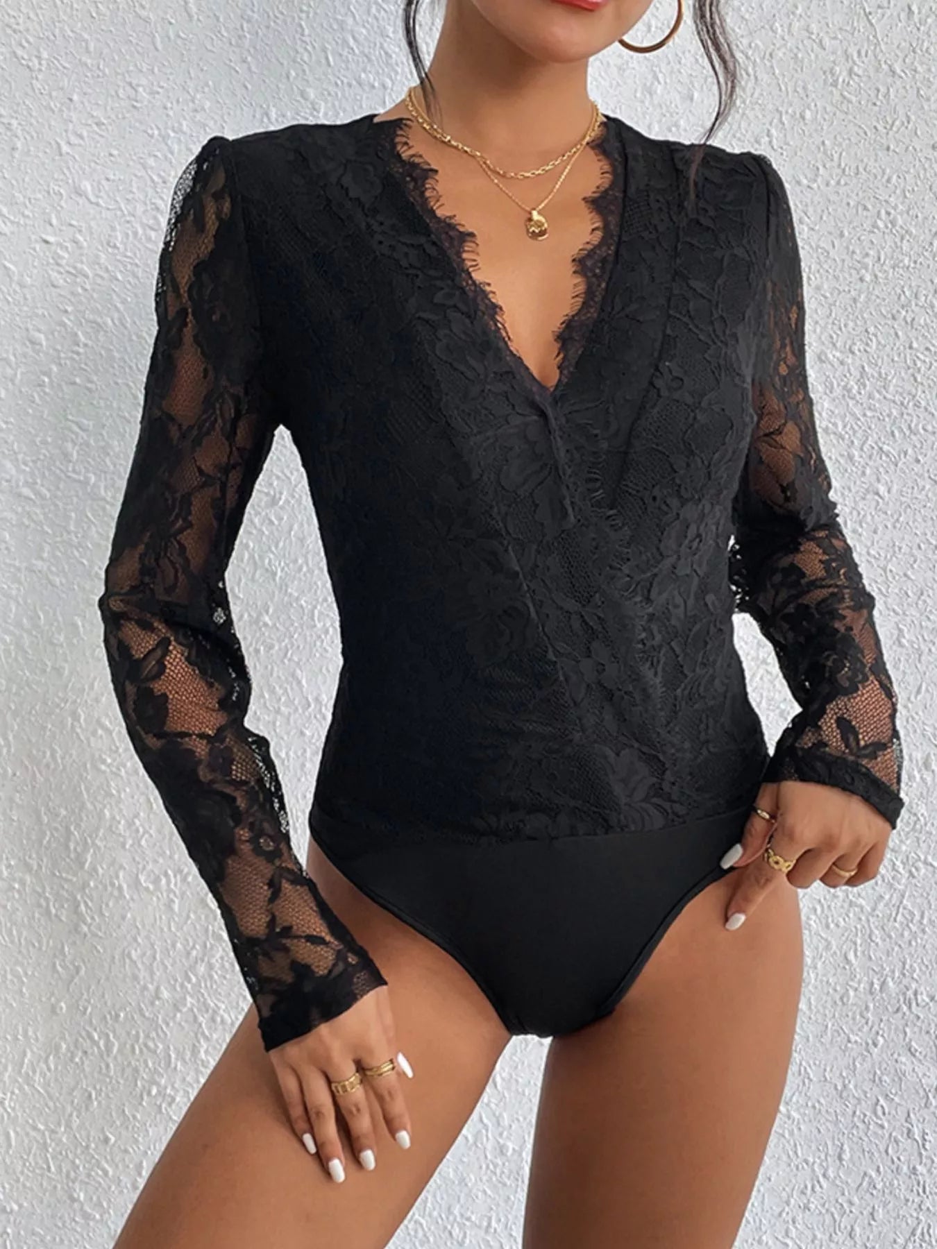 Black lace bodysuit worn by a model against a white background