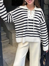 Person wearing a black and white striped hoodie with a plain background