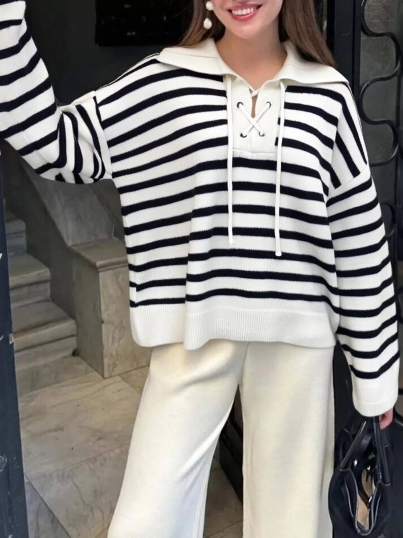 Person wearing a black and white striped hoodie with a plain background