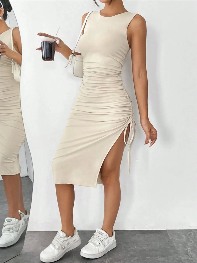 Woman wearing a beige dress with a slit, standing against a white background.