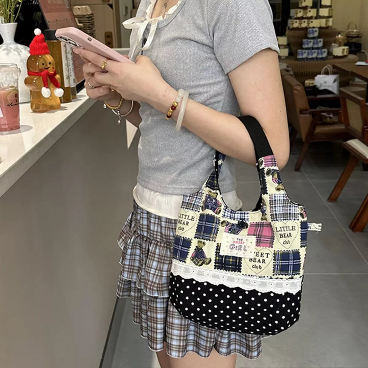 Person holding a plaid and polka dot handbag in a casual setting