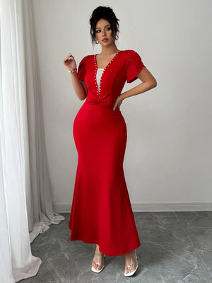 Woman wearing a red dress with a white collar against a neutral background