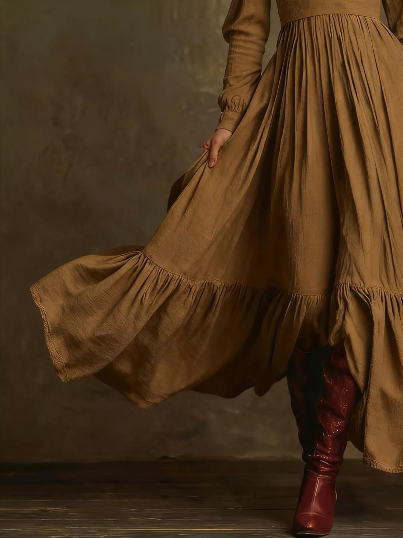 Person wearing a long brown dress with a flowing skirt and red boots against a dark background