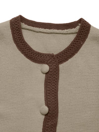 Close-up of a beige cardigan with brown ribbed trim and buttons on a white background