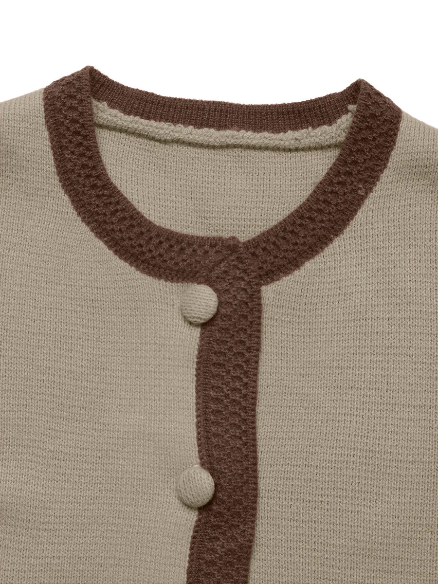 Close-up of a beige cardigan with brown ribbed trim and buttons on a white background