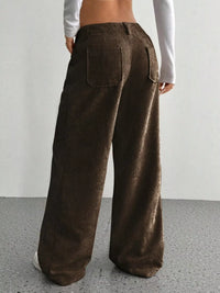 Brown corduroy pants worn by a person on a plain background