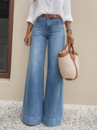 Person wearing blue jeans and a white shirt, holding a woven handbag.