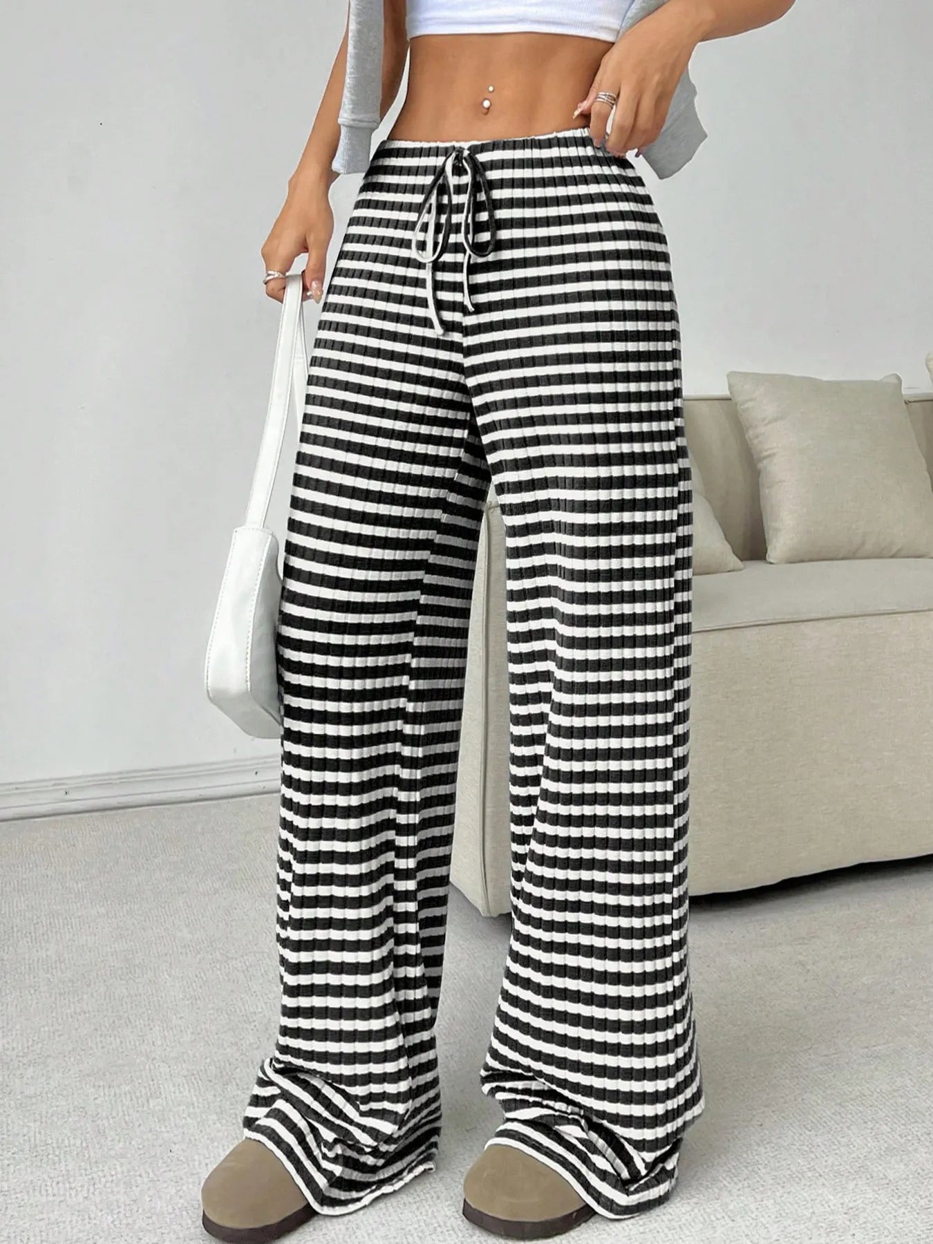 Person wearing black and white striped pants in a casual setting.