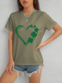 Person wearing a green t-shirt with a shamrock design on a plain background