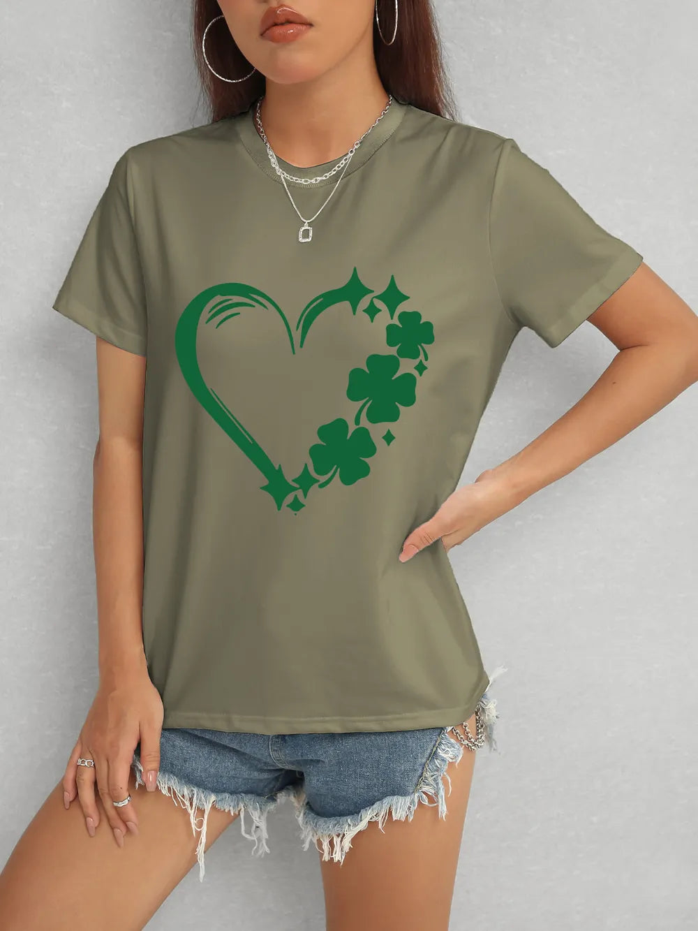 Person wearing a green t-shirt with a shamrock design on a plain background