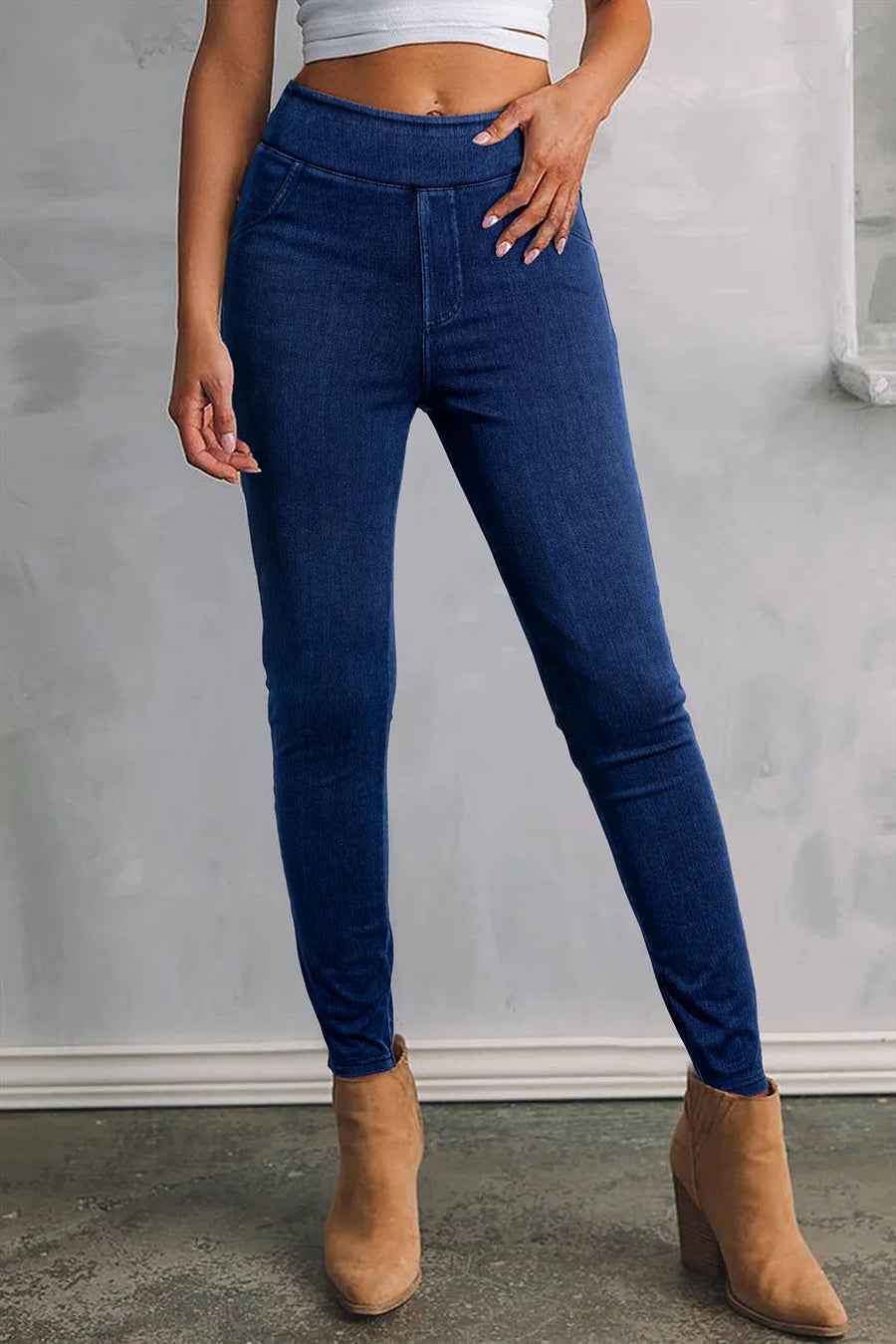 Person wearing blue jeans and tan boots against a gray background