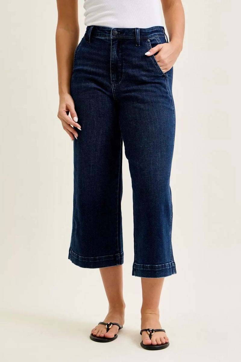 Person wearing dark blue jeans on a plain background
