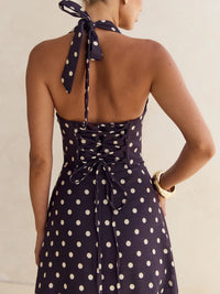 Navy blue dress with white polka dots featuring a halter neck design on a neutral background