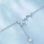 Silver necklace with star-shaped pendant on a light blue background