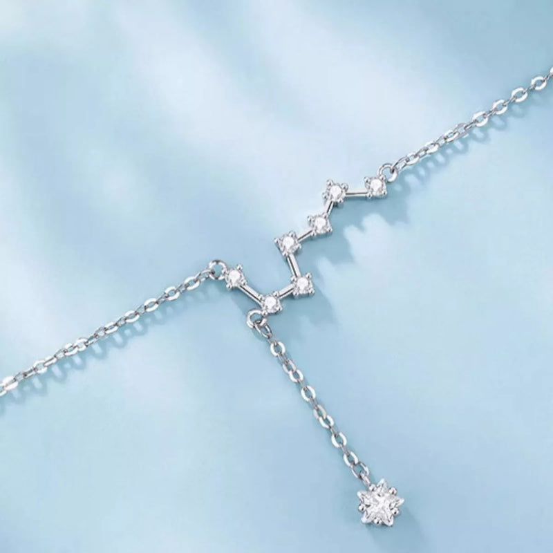Silver necklace with star-shaped pendant on a light blue background