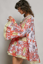Woman wearing a colorful floral dress against a plain background