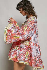 Woman wearing a colorful floral dress against a plain background