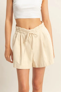 Beige shorts worn by a person on a plain background