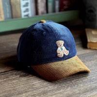 Blue and brown cap with a teddy bear emblem on a wooden surface