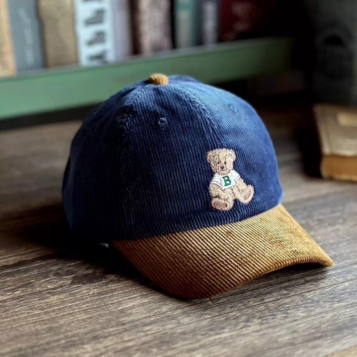 Blue and brown cap with a teddy bear emblem on a wooden surface