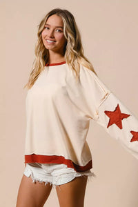 Woman wearing a cream-colored top with red star designs and shorts on a beige background