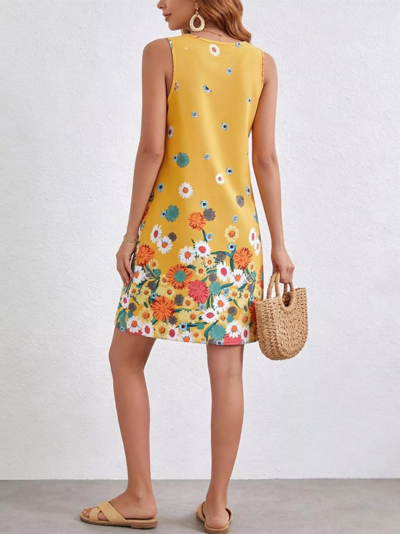 Woman wearing a yellow floral dress against a white background
