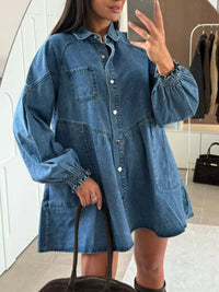 Person wearing a blue denim dress taking a mirror selfie.