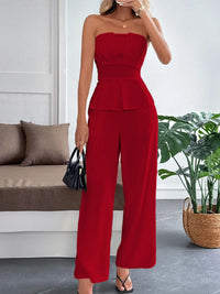 Woman wearing a red strapless jumpsuit in a living room setting.