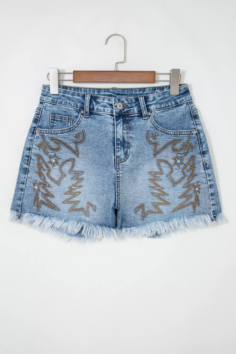 Blue denim shorts with fringe and embroidered designs on a white background