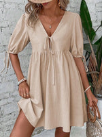 Woman wearing a beige dress with a white brick wall background