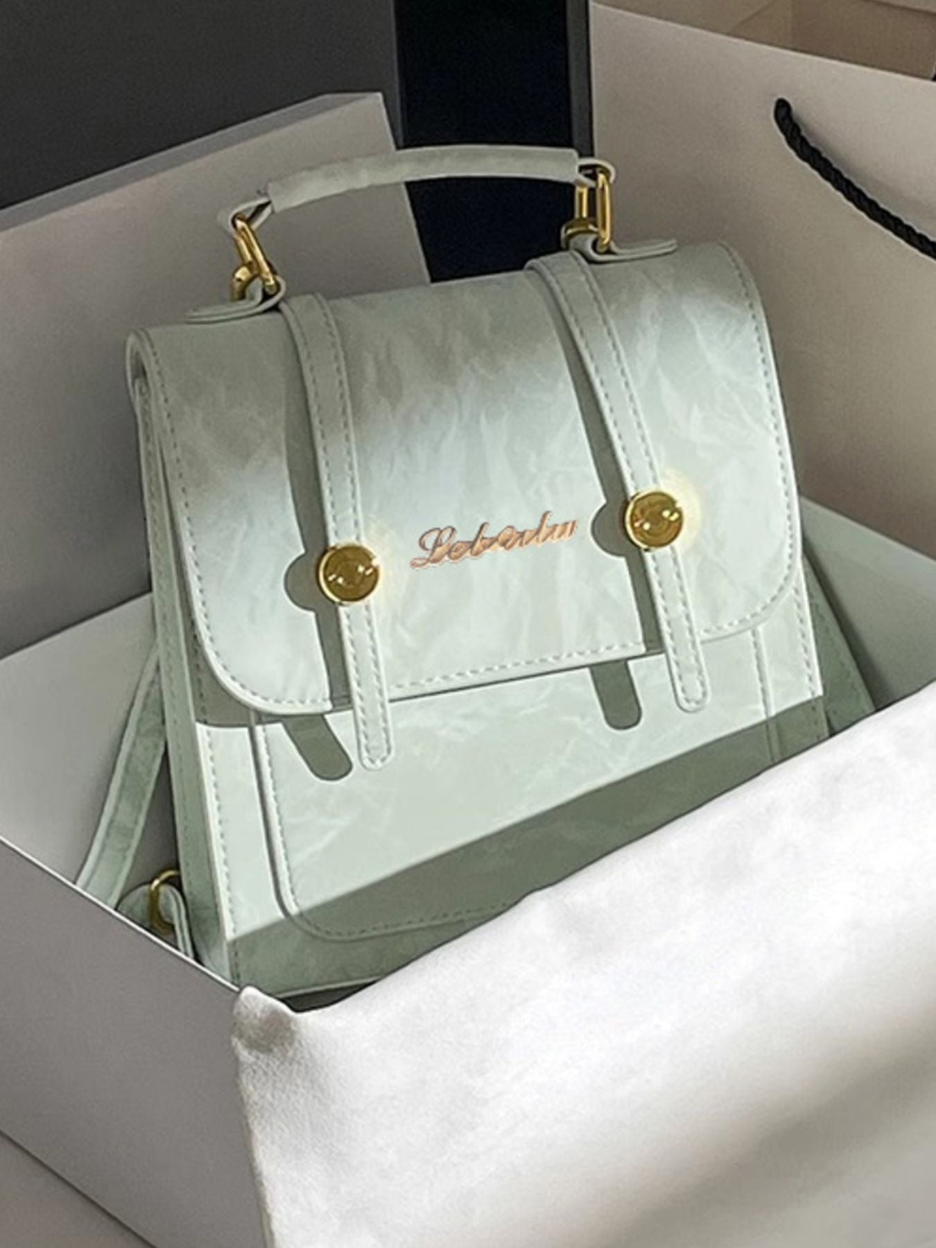 Light blue handbag with gold accents on a white surface