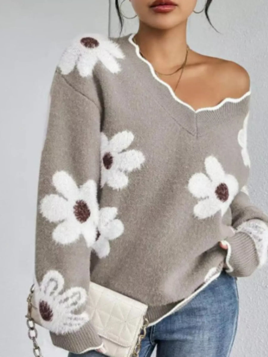 Gray sweater with white floral patterns worn by a person on a plain background