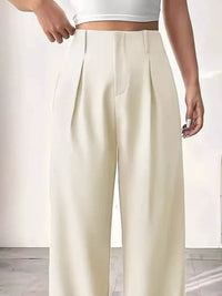 Person wearing white wide-leg pants and a white top on a light background