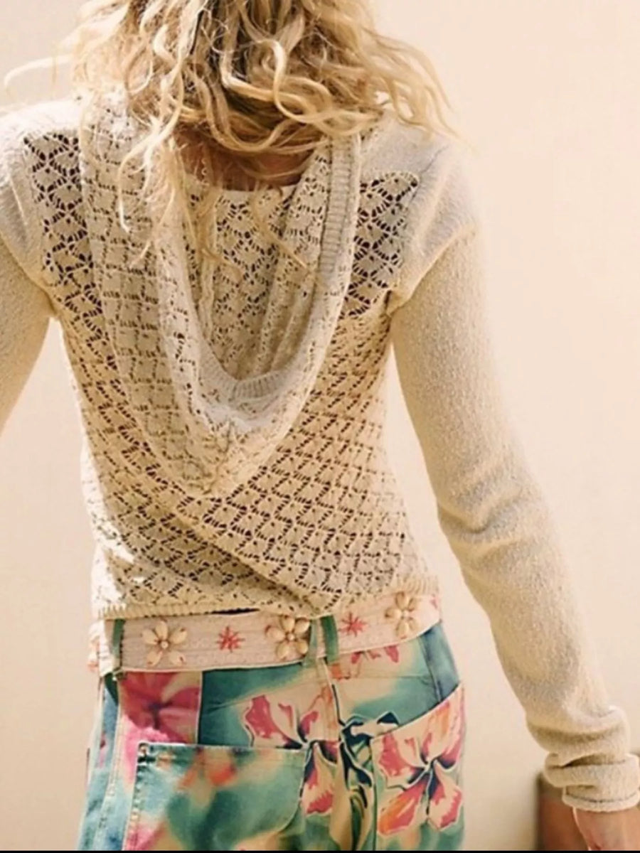 Person wearing a light-colored lace top and colorful floral skirt.