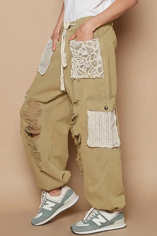 Person wearing beige cargo pants with lace detailing on a beige background