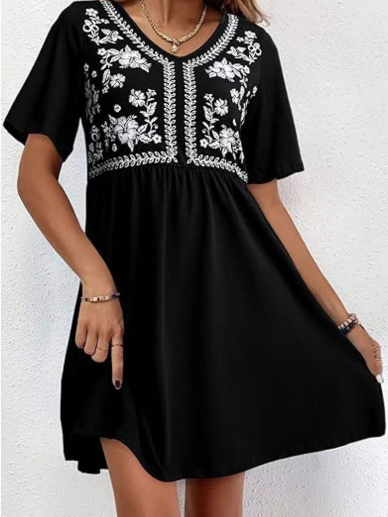 Black dress with white floral embroidery on a white background