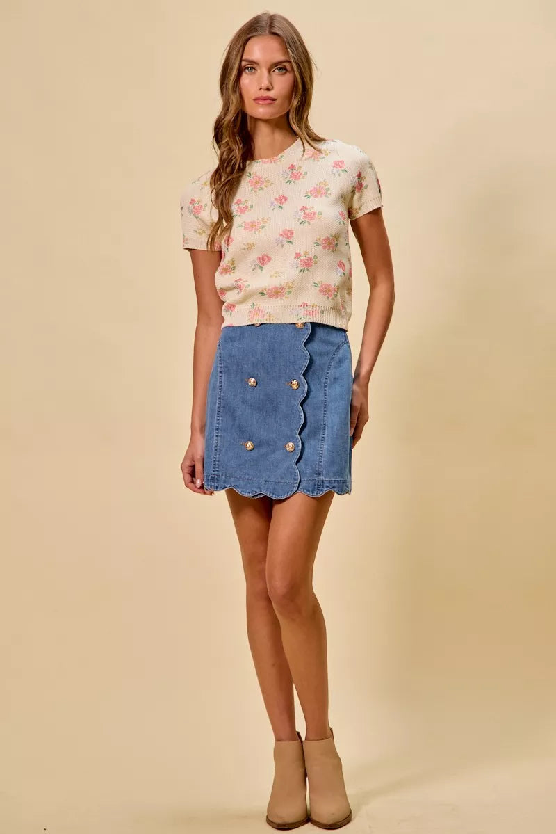 Woman wearing a floral top and denim skirt on a beige background