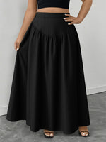 Person wearing a black skirt on a gray floor with a white wall background