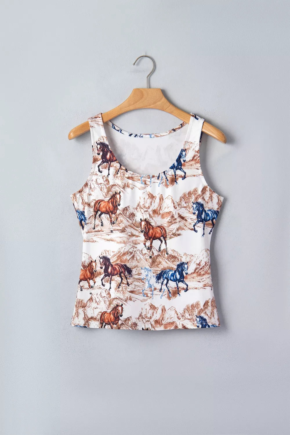 Tank top with horse print on a hanger against a gray background