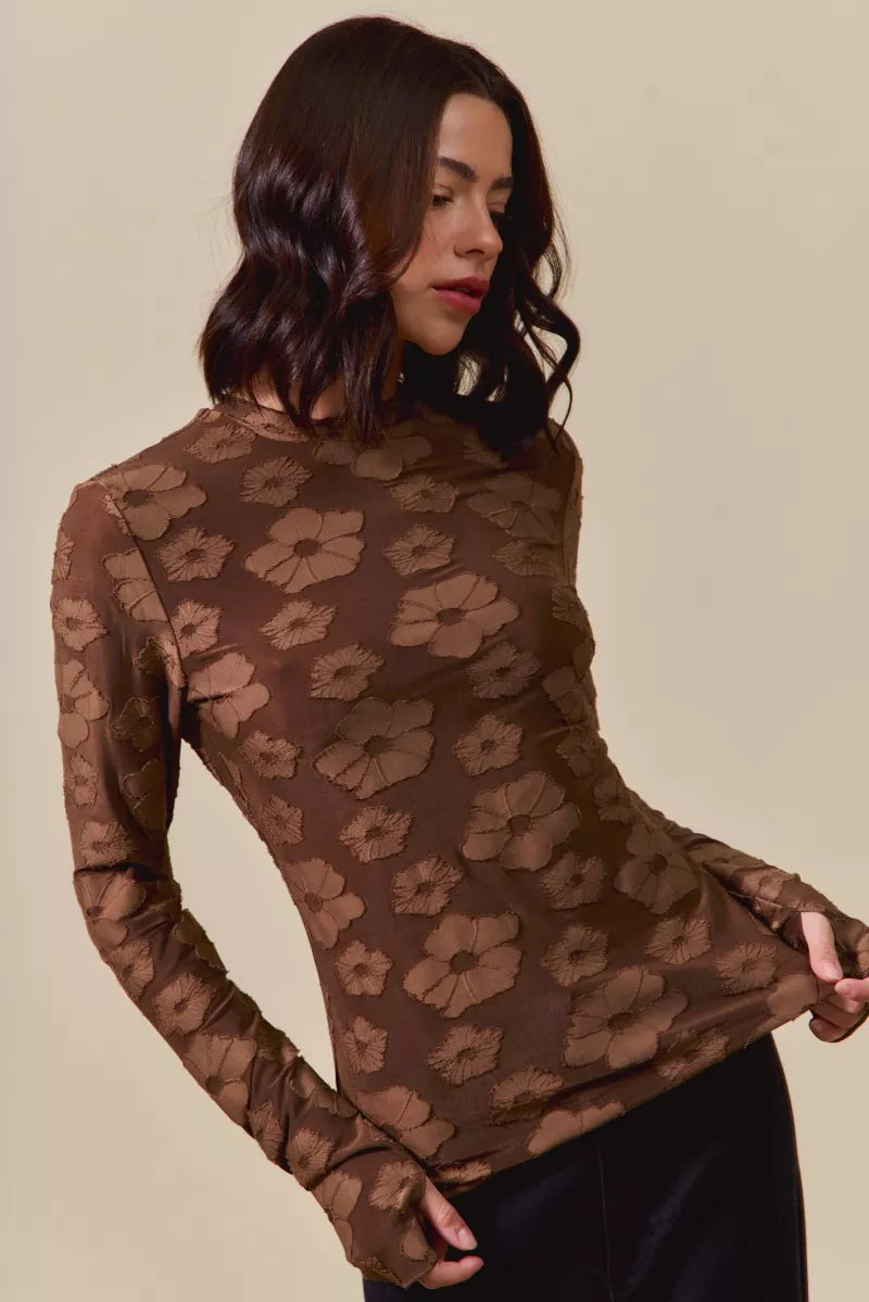 Woman wearing a brown floral patterned top against a beige background