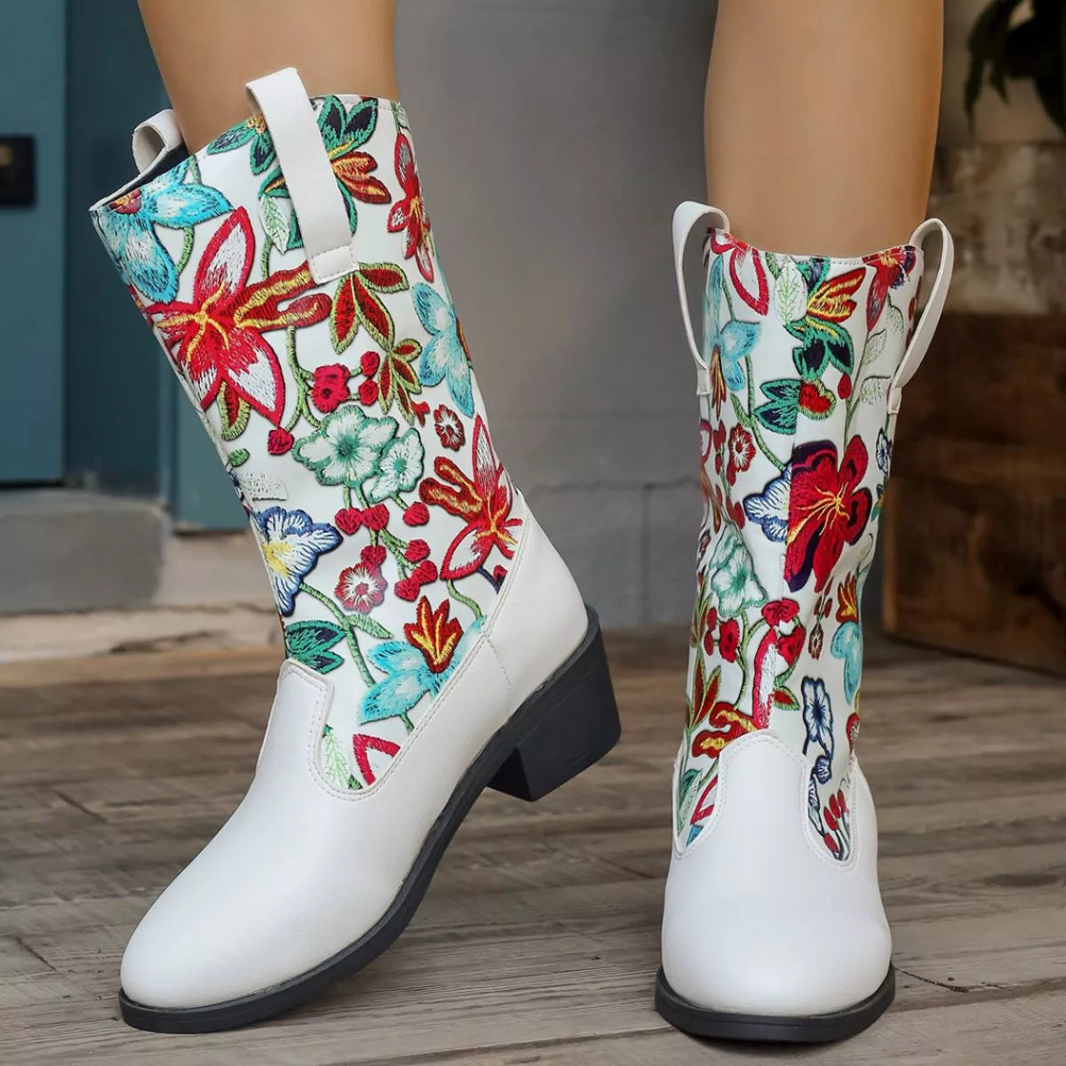 White boots with colorful floral patterns on a wooden floor.