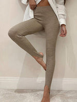 Person wearing beige ribbed leggings with a white shirt in a minimal indoor setting