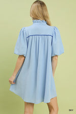 Woman wearing a light blue dress against a green background