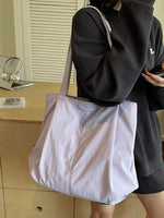 Person holding a light purple tote bag with 'JUUN.J' branding in an indoor setting.